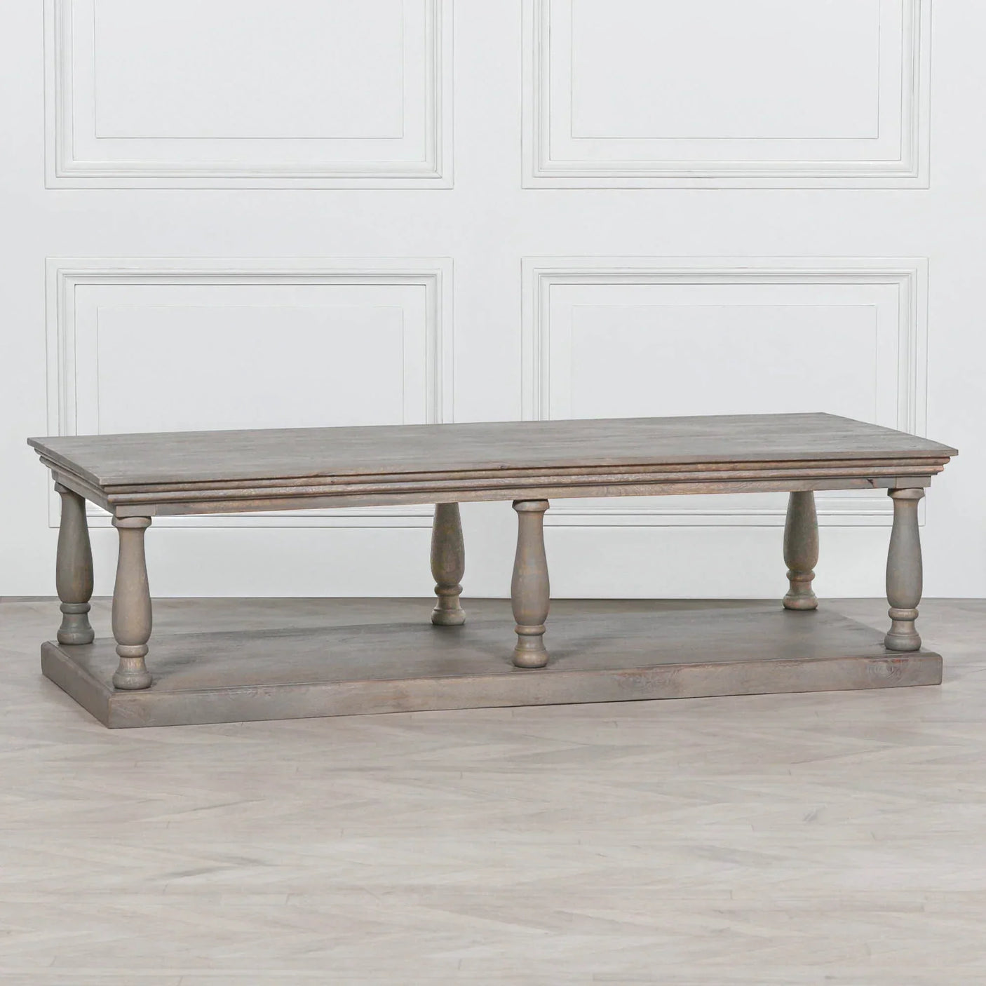 Rustic wood coffee table with turned legs and lower shelf on light wood floor