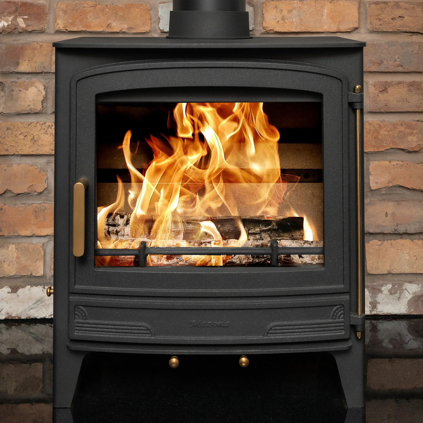 Black wood burning stove with flames, set against a brick wall background