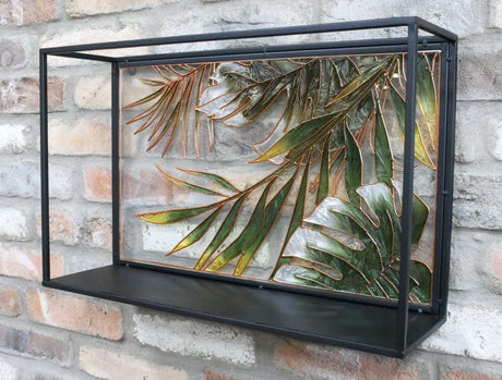 Metal wall shelf with tropical leaf design and black frame mounted on brick wall