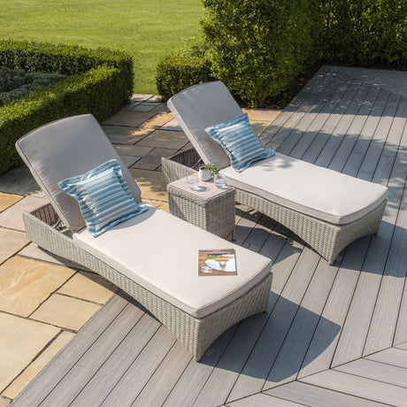 Rattan sun loungers with grey cushions and blue striped pillows on garden decking