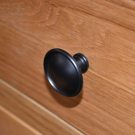 black metal drawer handle on oak wood furniture surface