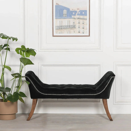 Black velvet bench with tufted seat, studded trim, and wooden legs in modern interior