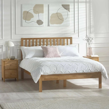 Oak double bed frame with slatted headboard, white bedding, and bedside tables in bright bedroom