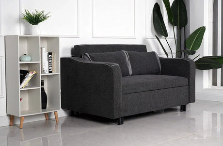 Dark grey fabric sofa with matching cushions in modern living room next to white bookshelf