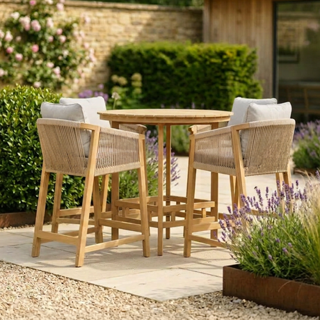 Wooden outdoor bar table set with woven chairs and grey cushions on patio