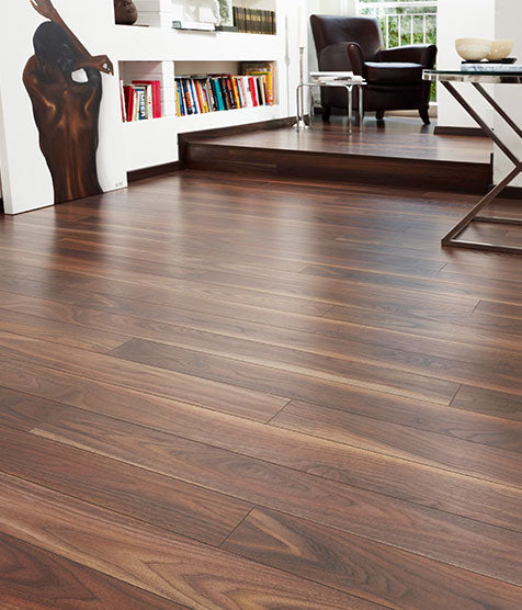 Dark wood flooring in living room with bookshelf, armchair, and modern decor
