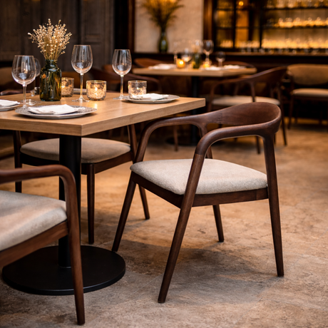 Tess chair with curved wooden frame and beige upholstered seat at dining table setting