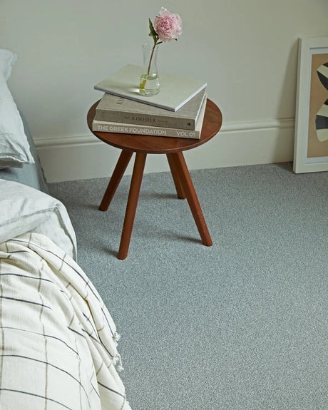Soft grey carpet in bedroom styled with wooden side table and books — cozy and inviting