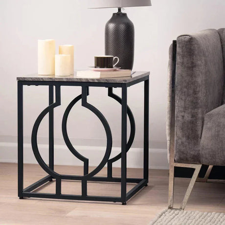Modern geometric side table with black metal frame beside grey sofa in living room