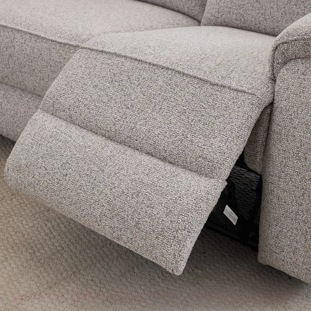 Light grey manual recliner sofa footrest extended on textured carpet floor
