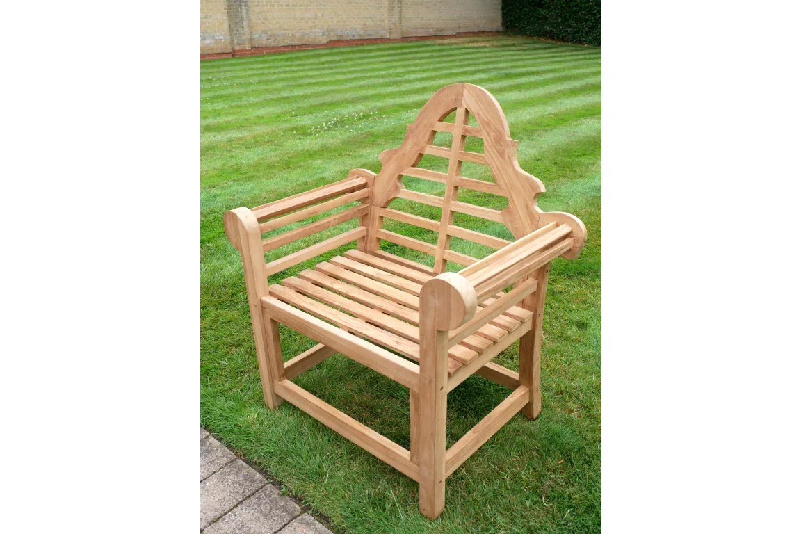 Teak garden chair with slatted seat and decorative arched backrest on lawn