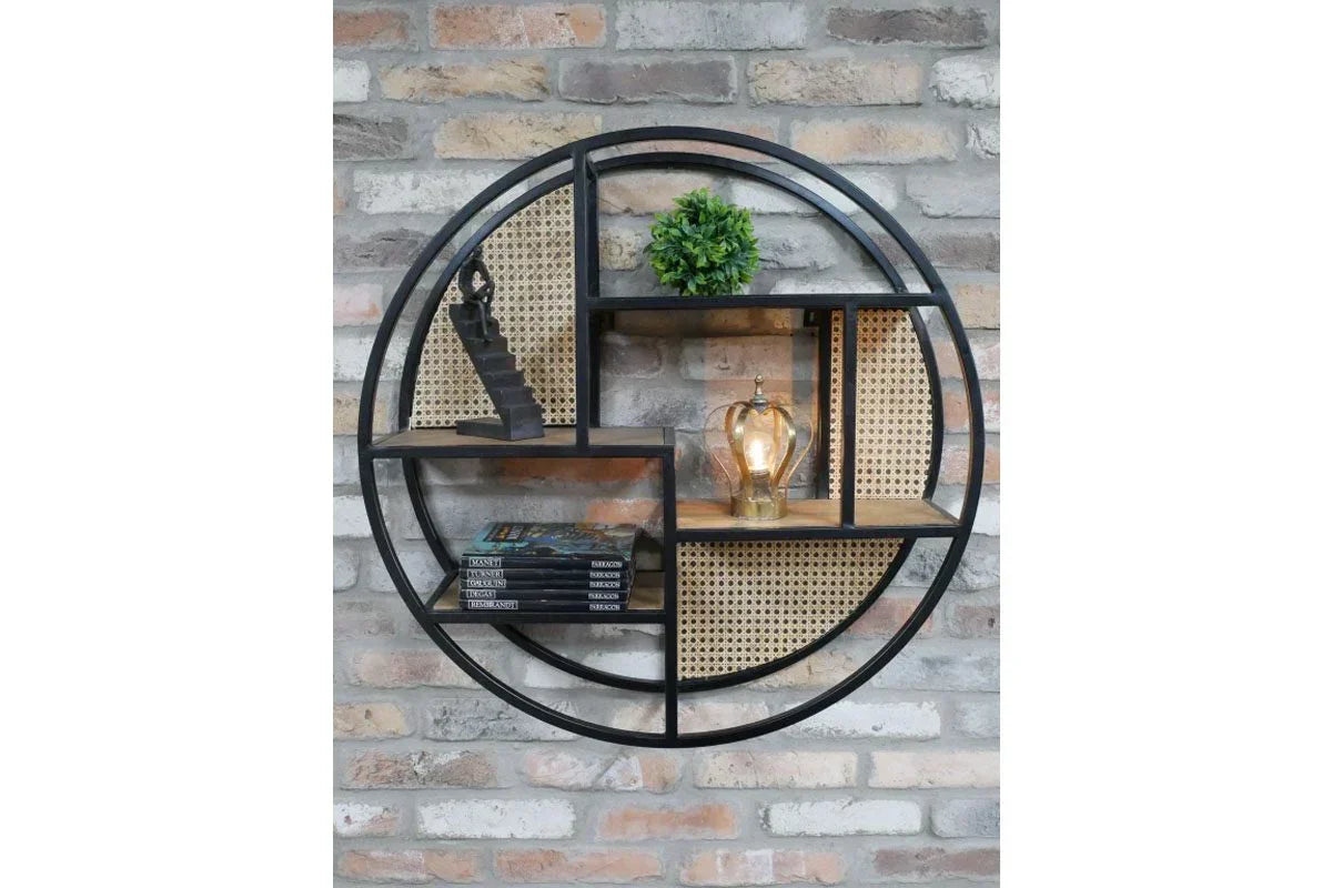 Round metal wall shelf with cane panels holding books, plant, decor and lamp on brick wall