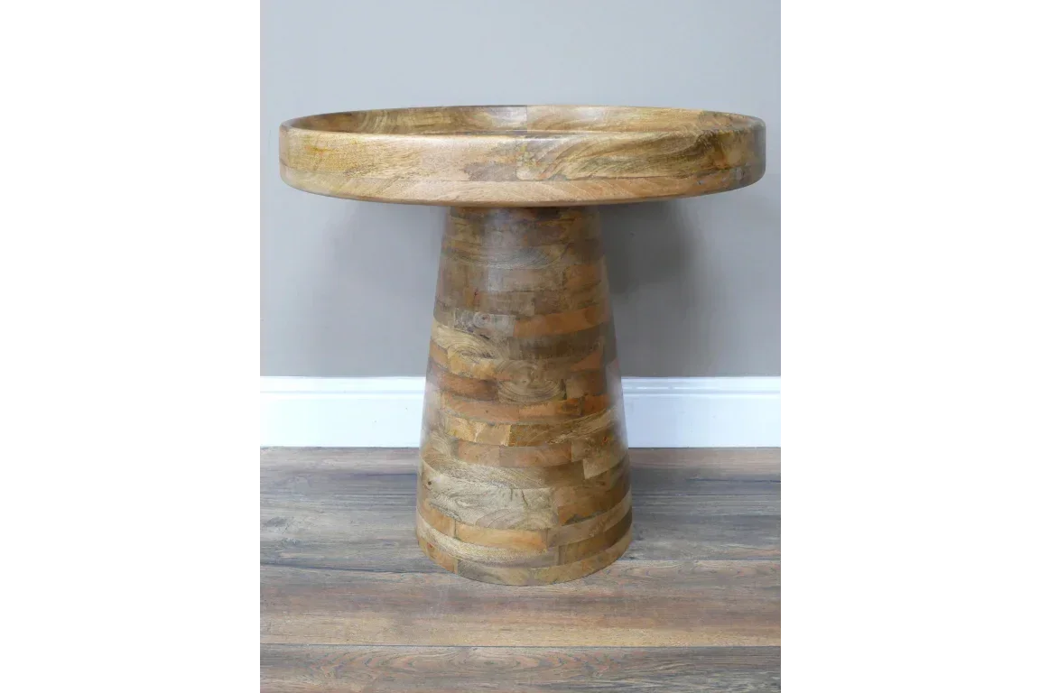 Round mango wood side table with pedestal base on wooden floor