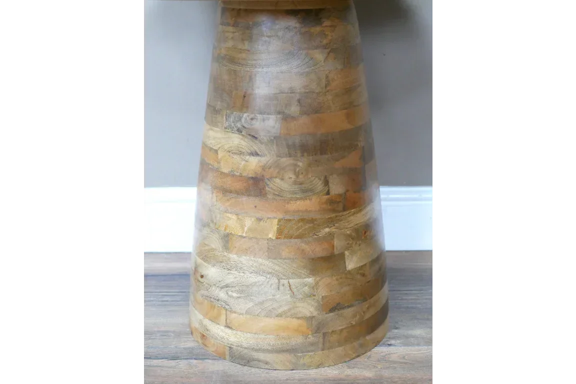 Closeup of round wooden dining table base with natural grain and banded pattern on wood floor