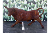 Rust effect bull garden sculpture on outdoor surface with leaf mural background
