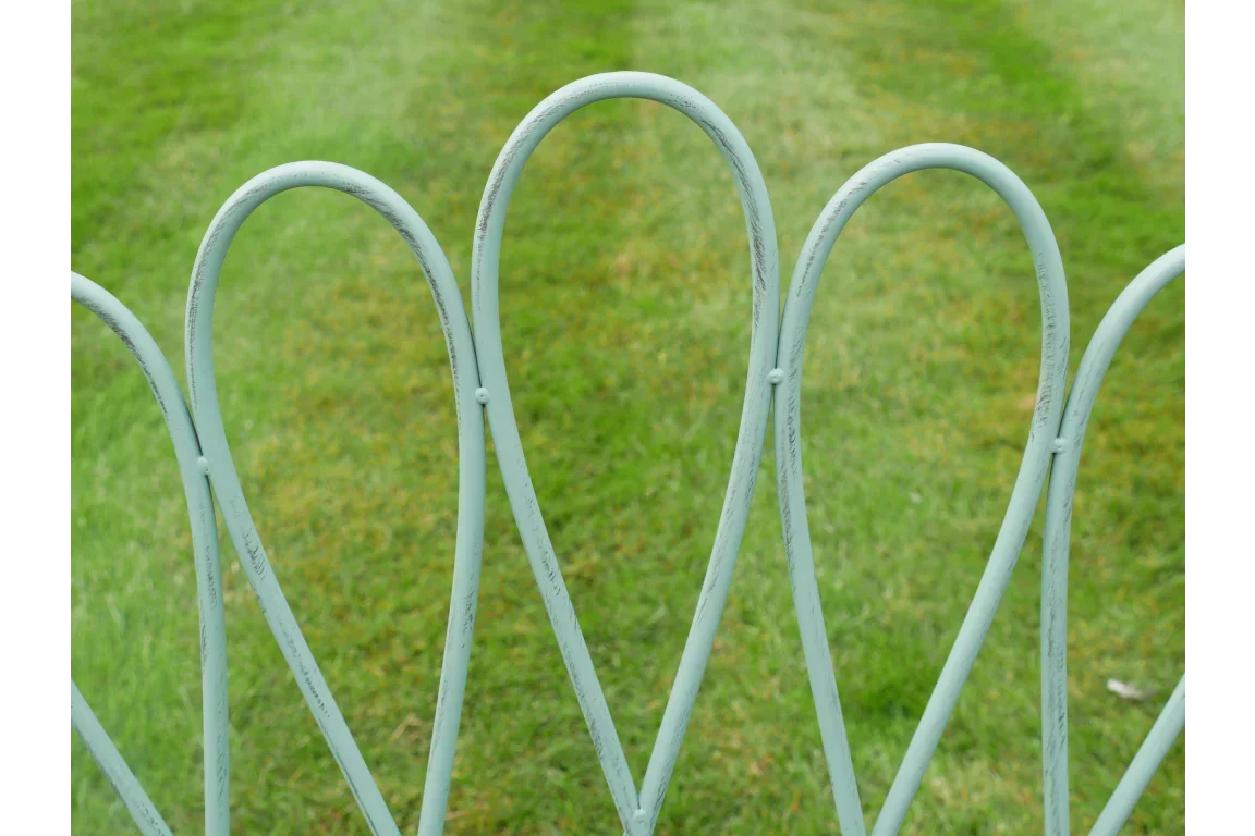 pale green metal garden fence panels with decorative arch design on grass lawn