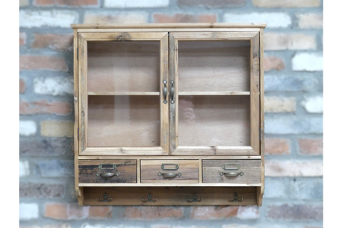 Wooden wall unit with two glass-front doors, three drawers, and four metal hooks, shown mounted on brick wall.