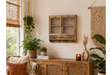 Rustic wooden wall unit with glass doors, three drawers, and four hooks, mounted on beige wall in cozy room setting.