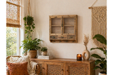 Rustic wooden wall unit with glass doors, three drawers, and four hooks, mounted on beige wall in cozy room setting.