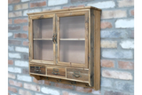 Wooden wall unit with glass double doors, three drawers, and four metal hooks, angled left view on brick wall.
