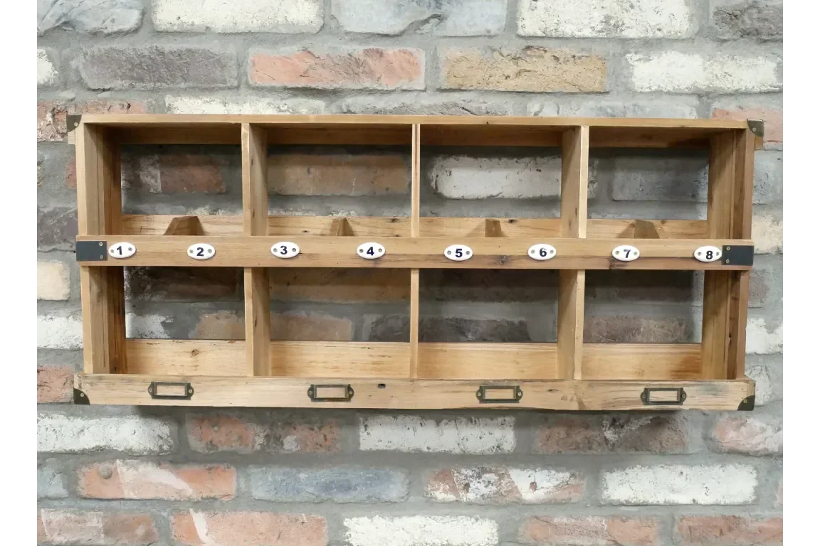 Rustic wooden wall shelf with eight numbered cubby compartments against brick wall