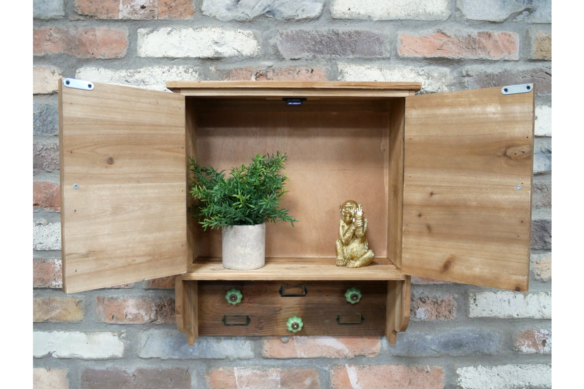 Wall-mounted wooden wall unit with two open doors, shelves, four hooks with green ceramic knobs, on brick wall.
