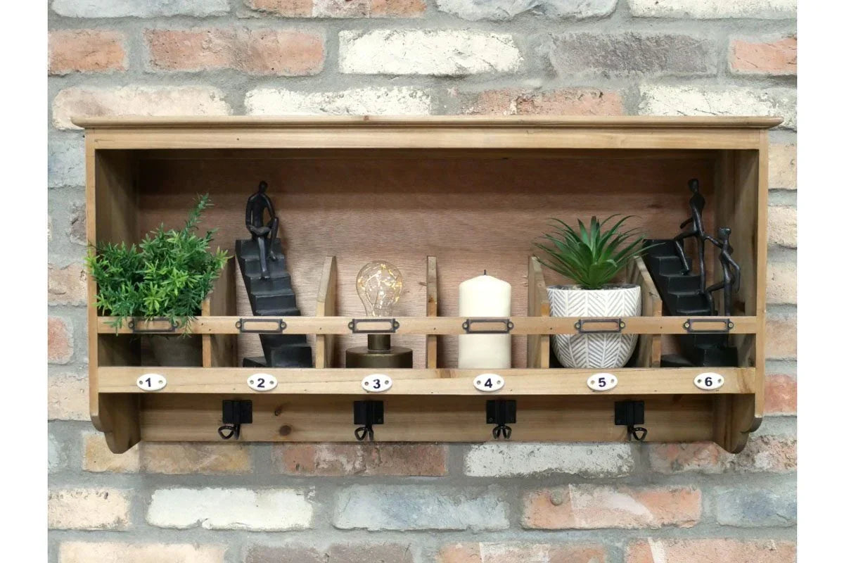 Wall mounted wooden shelf with numbered hooks, potted plants, decor, and candle on brick wall