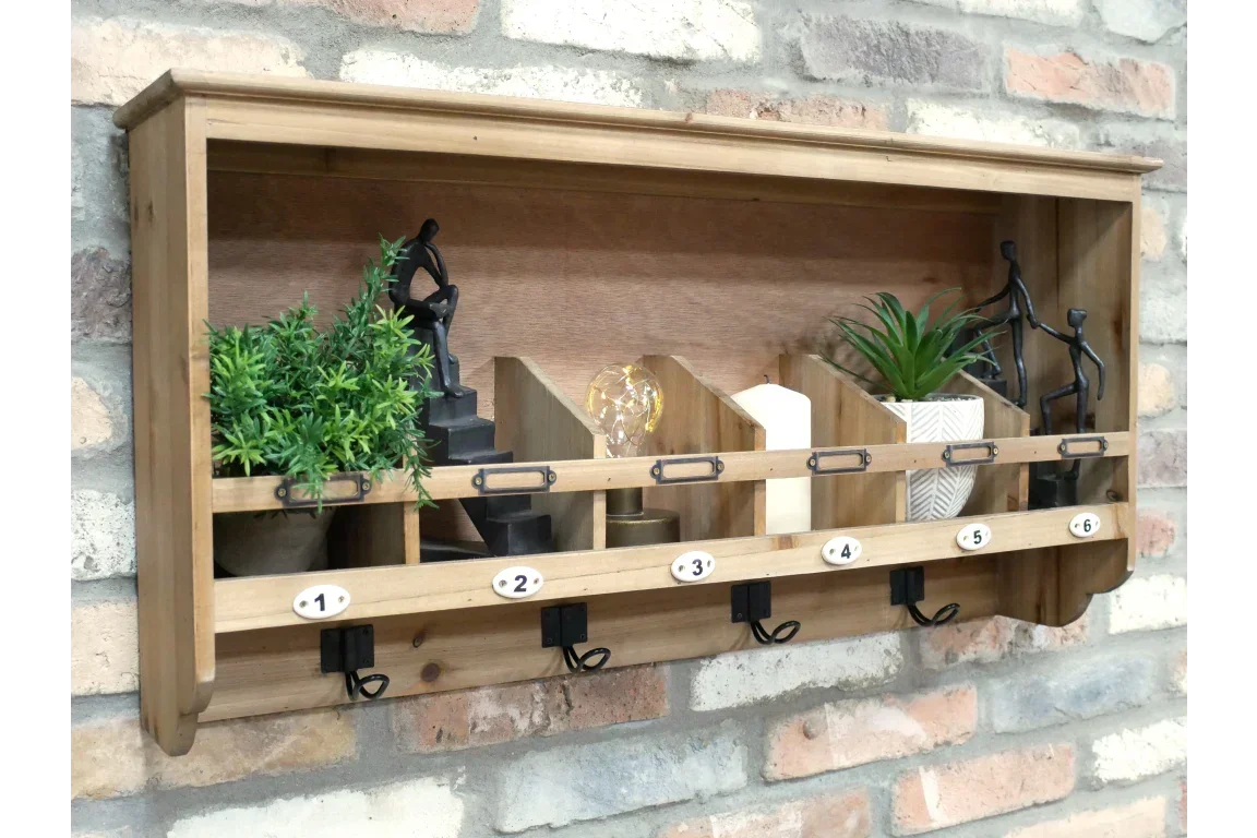 Wooden wall shelf with six numbered hooks, decorative plants, and ornaments on brick wall