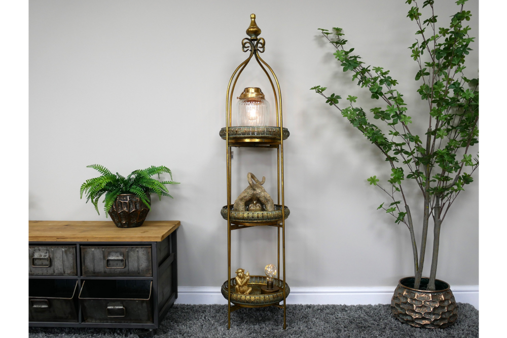 Tall 3 tier metal shelves with decorative items, displayed in a room with grey carpet and potted plants.