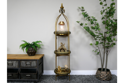 Tall 3 tier metal shelves with decorative items, displayed in a room with grey carpet and potted plants.