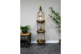 Tall narrow 3 tier metal shelves with gold finish, decorative trays, displayed in room with plants and grey carpet.