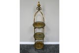 Tall 3 tier metal shelves with decorative round trays in gold and green finish, standing on gray carpet.