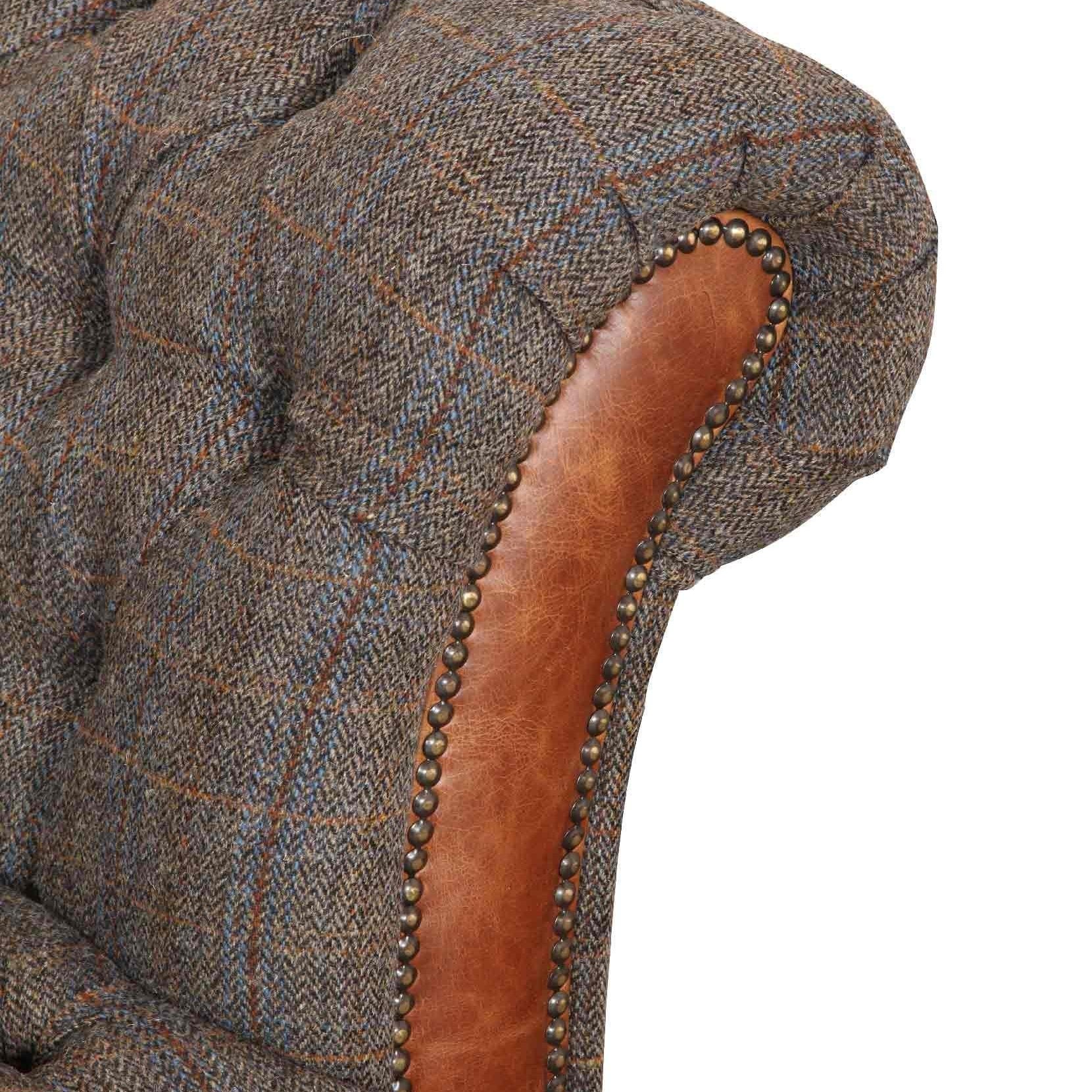 Close-up of tufted fabric and brown leather sofa arm with studded trim