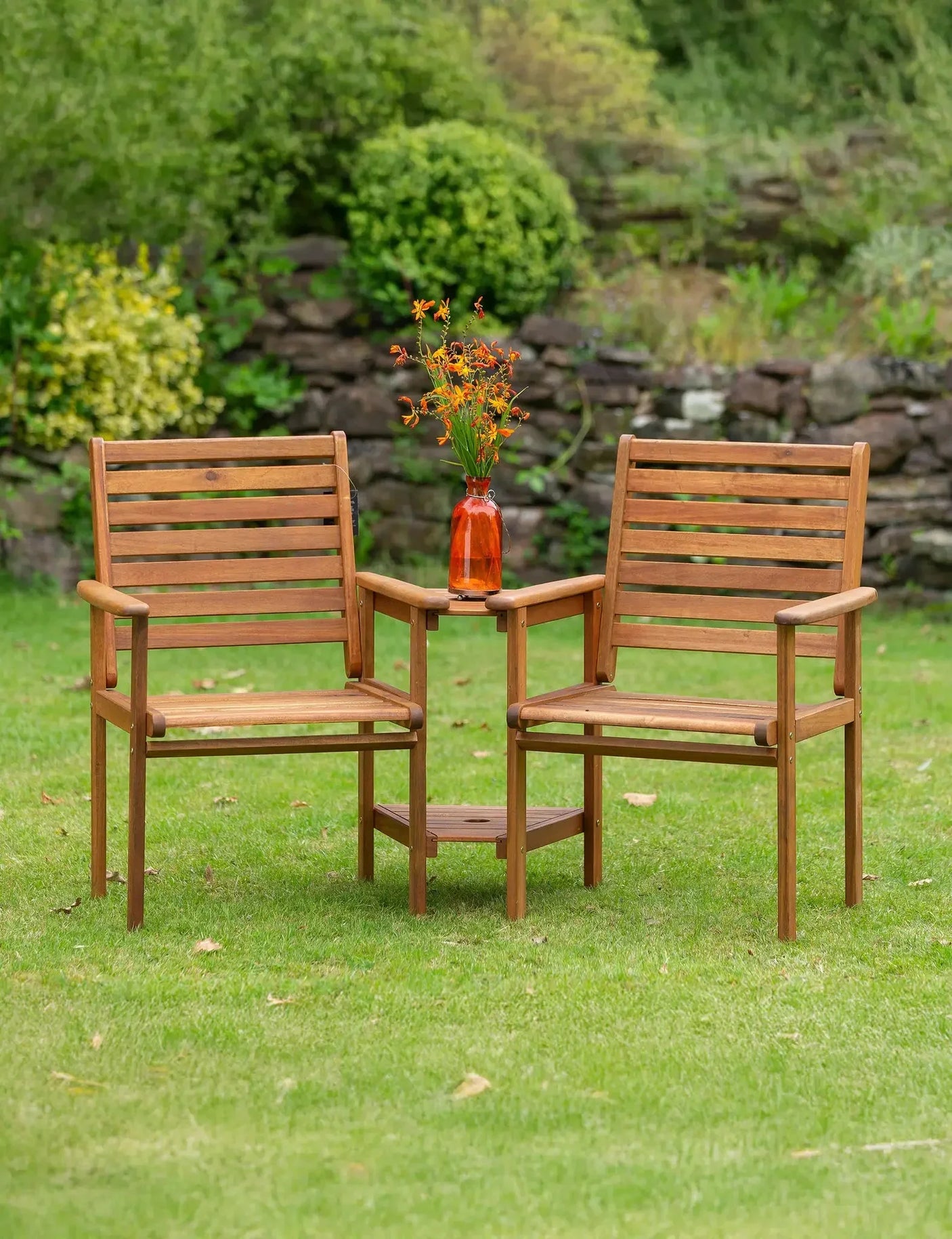 Wooden garden companion bench set with built-in table and orange vase on lawn