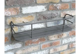 Wall-mounted grey metal shelf with raised bars, angled view against a textured brick wall background.