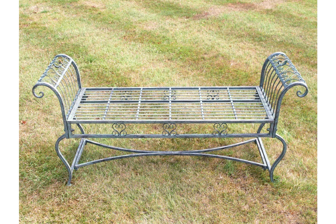 Metal garden bench with ornate armrests on grass
