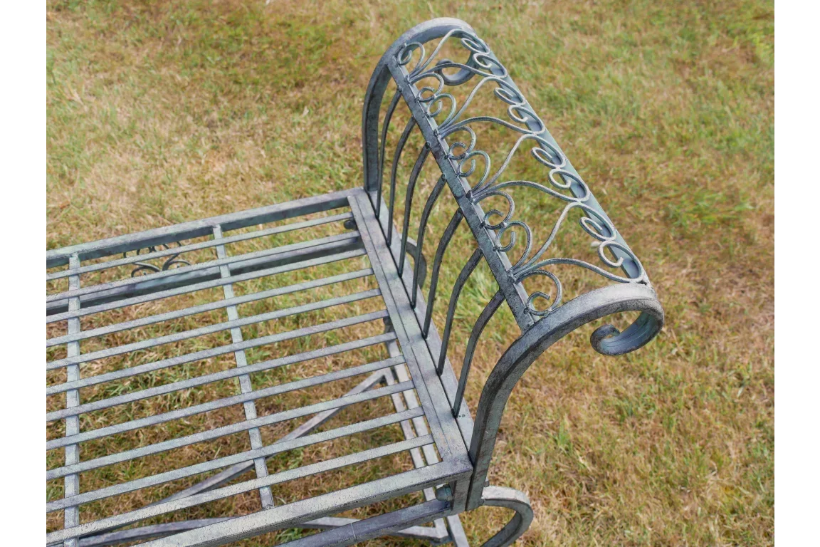Metal garden bench with scroll armrest and slatted seat on grass