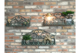 Set of 3 green wrought iron wall shelves with decorative scrollwork, displayed on a brick wall with small plants and