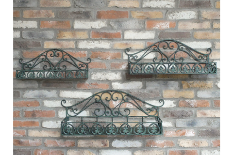 Set of 3 green metal wall shelves with ornate scrollwork detail, mounted on a rustic brick wall, viewed from the front.