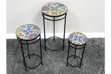 Set of 3 round side tables with black metal legs and colorful patterned ceramic tile tops on gray carpet.