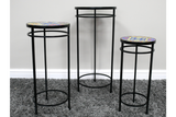 Set of 3 black metal side tables with colorful mosaic tile tops, displayed on gray carpet against a white wall.