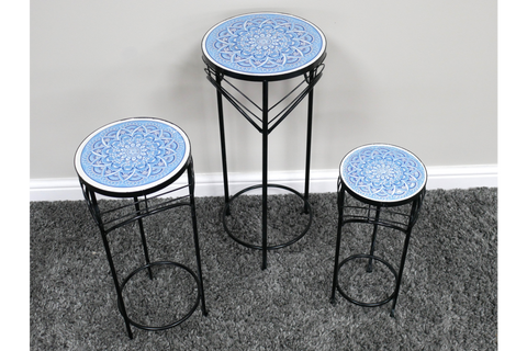 Set of three black metal side tables with round blue and white patterned tops, displayed on gray carpet.