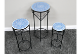 Set of three black metal side tables with round blue and white patterned tops, displayed on gray carpet.