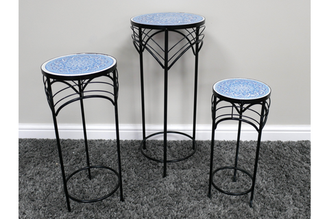 Set of three black metal side tables with blue patterned round ceramic tops, shown at front angle on gray carpet.