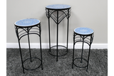 Set of three black metal side tables with blue patterned round ceramic tops, shown at front angle on gray carpet.