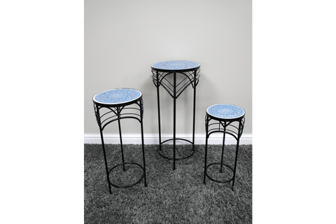 Set of 3 round side tables with black metal legs and blue patterned ceramic tops, shown on gray carpet against white wall.