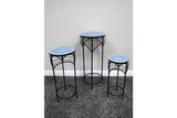 Set of 3 round side tables with black metal legs and blue patterned ceramic tops, shown on gray carpet against white wall.