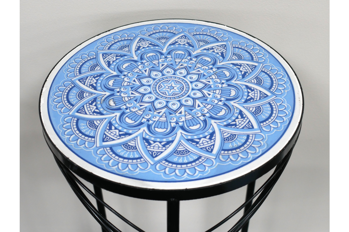 Round side table with black metal frame and blue and white intricate mandala tile top, angled view.
