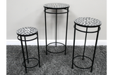 Set of 3 round black metal side tables with mosaic tile tops in varying heights on a gray carpet.