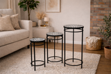 Set of 3 round side tables with black metal frames and mosaic stone tops, shown from front angle in living room.
